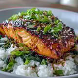 Golden-broiled Miso Glazed Salmon Bowl with caramelized edges rests on fluffy rice and bright spinach, garnished with green onions and sesame.