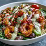 This vibrant Mediterranean Shrimp Bowl features juicy shrimp, tomatoes, cucumber, and olives with a zesty lemon garnish.