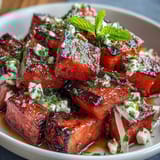 A vibrant summer dish of grilled watermelon, creamy feta, and aromatic mint, drizzled with balsamic glaze for a sweet-tart finish.