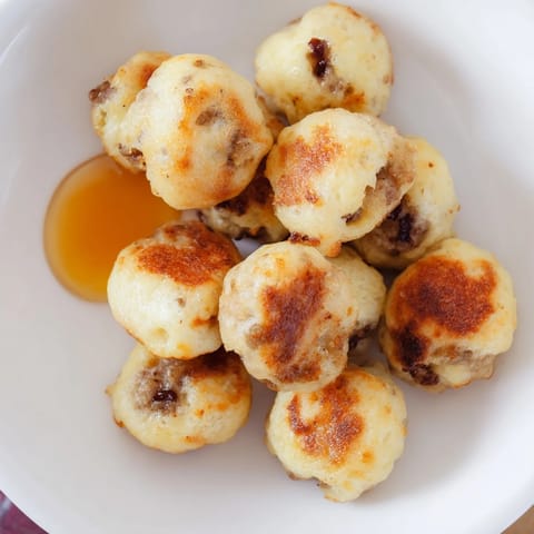 Fluffy mini pancake bites, some bulging with savory sausage, promising a delicious breakfast.