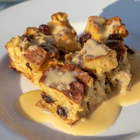 Homemade bread pudding, baked until bubbly and tender, is drizzled with a decadent creamy sauce.