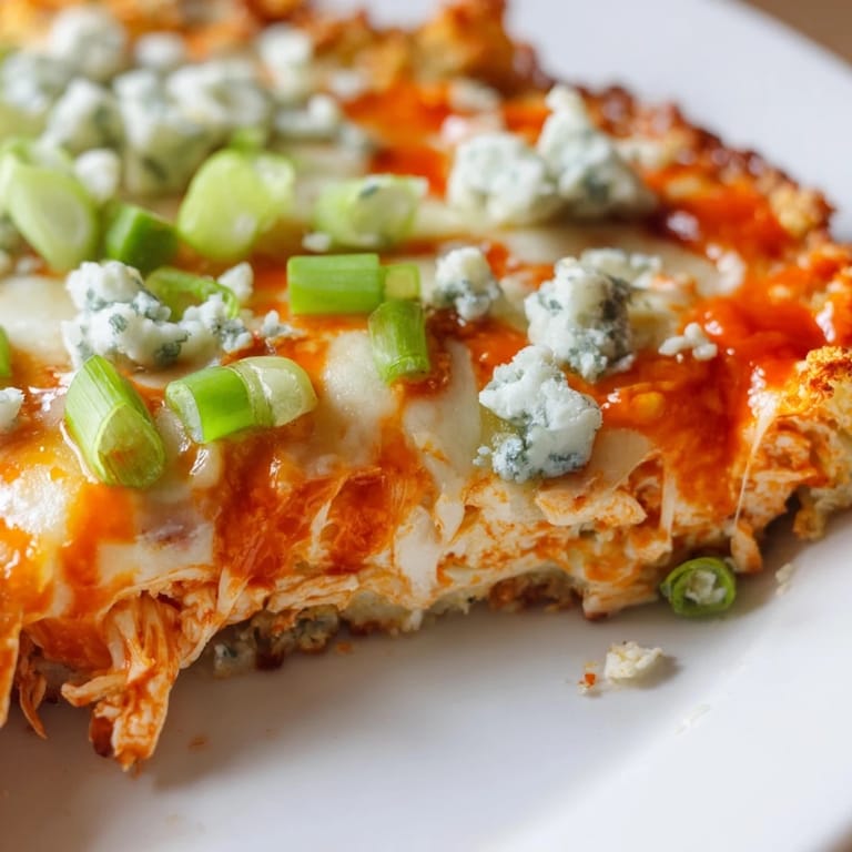 This vegetarian Buffalo Cauliflower Pizza shows a cheesy, bubbly crust with sliced green onions and celery, perfect for a gluten-free game day meal.