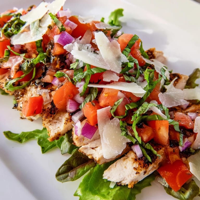 Bright Bruschetta Chicken Salad features golden grilled chicken breasts arranged over crisp greens with a fresh tomato-basil topping.