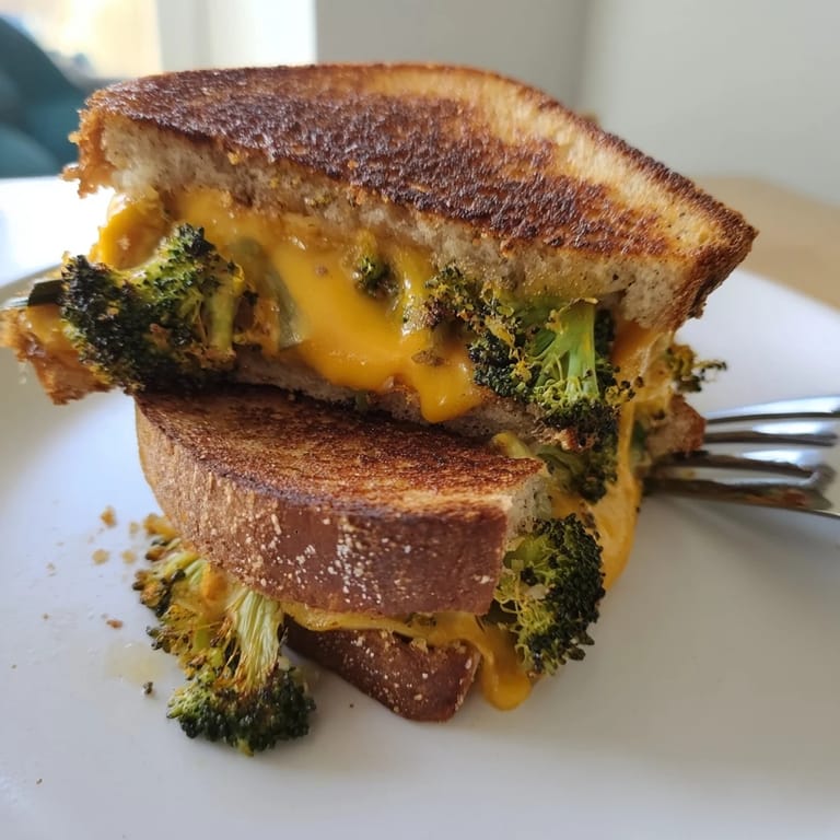 A rustic, homemade sandwich on whole wheat bread, featuring crispy edges and caramelized broccoli for a comforting lunch.