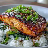 Golden-broiled Miso Glazed Salmon Bowl with caramelized edges rests on fluffy rice and bright spinach, garnished with green onions and sesame.