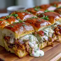 Warm sliders with turkey, bacon, and creamy Mornay sauce on soft brioche buns, garnished with fresh parsley.