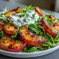 Grilled peaches and burrata salad with honey, arugula, and balsamic drizzle, a perfect summer dish.